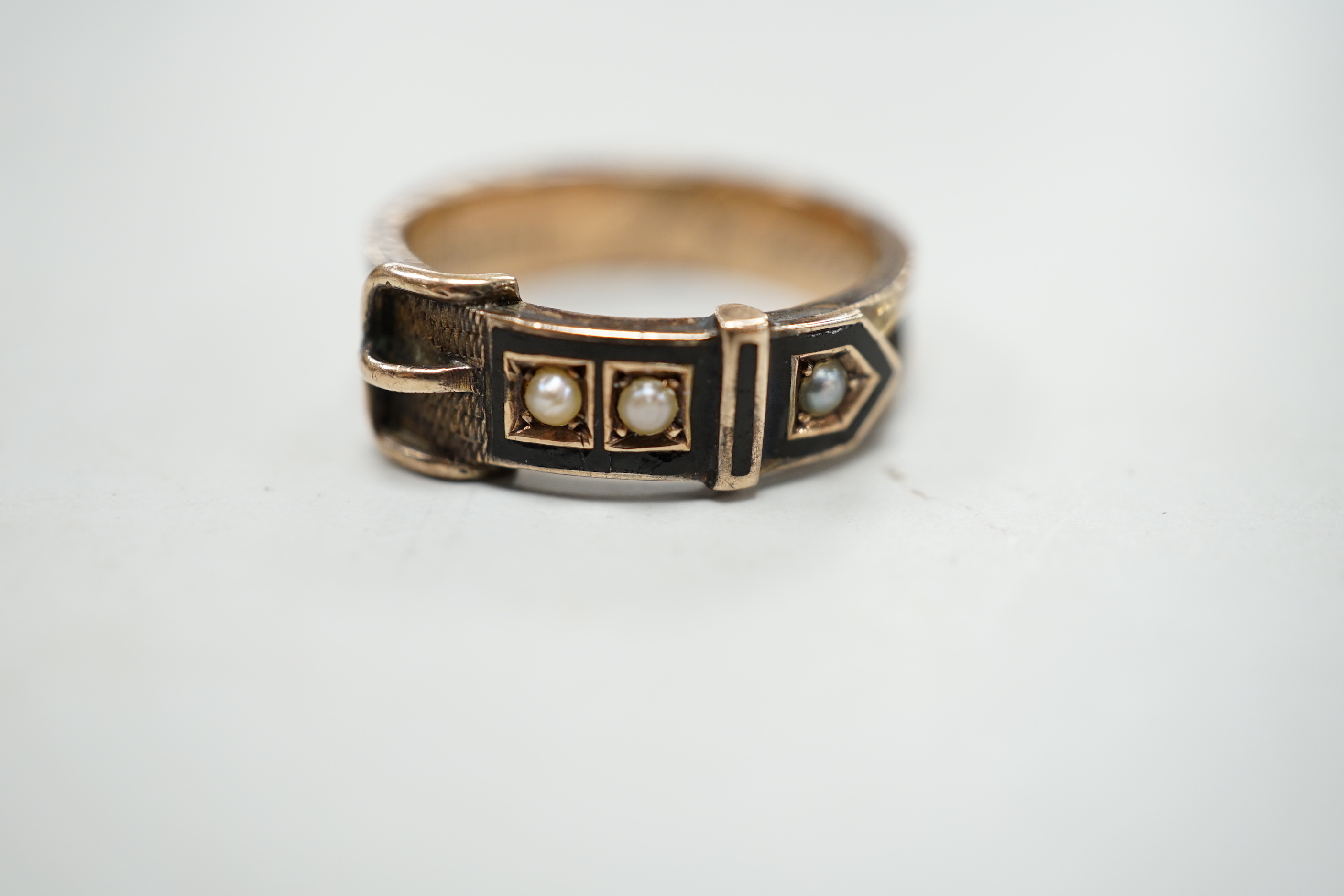 A Victorian 9ct gold, black enamel, plaited hair and seed pearl set mourning buckle ring, size P and a similar yellow metal brooch